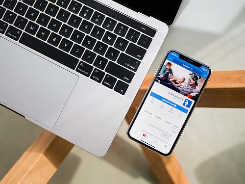 social media iPhone X beside MacBook app